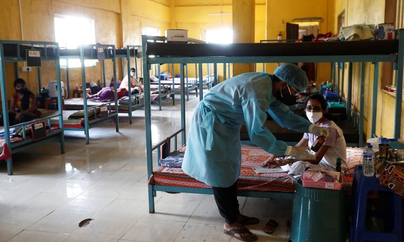 In this file photo, a doctor checks the medicines of a patient suffering from Covid-19 inside a classroom turned coronavirus care facility on the outskirts of Mumbai, India.&mdash; Reuters