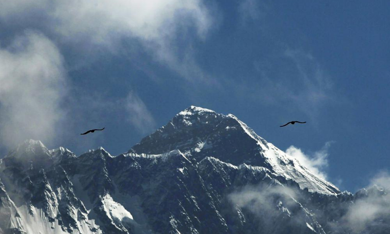 Birds fly as Mount Everest is seen from Namche Bajar, Solukhumbu district, Nepal. &mdash; AP
