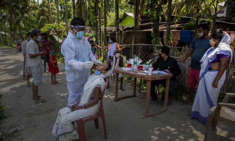 An Indian health worker in a protective suit takes the swab of a village woman to test for Covid-19 in Burha Mayong village, Morigaon district of Assam, India, May 22. &mdash; AP