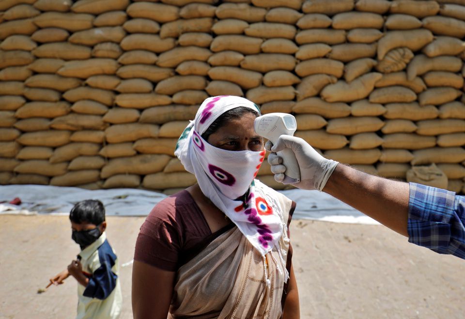 A healthcare worker checks the temperature of a rice mill worker during a coronavirus vaccination drive at Bavla village on the outskirts of Ahmedabad, India, April 13. — Reuters