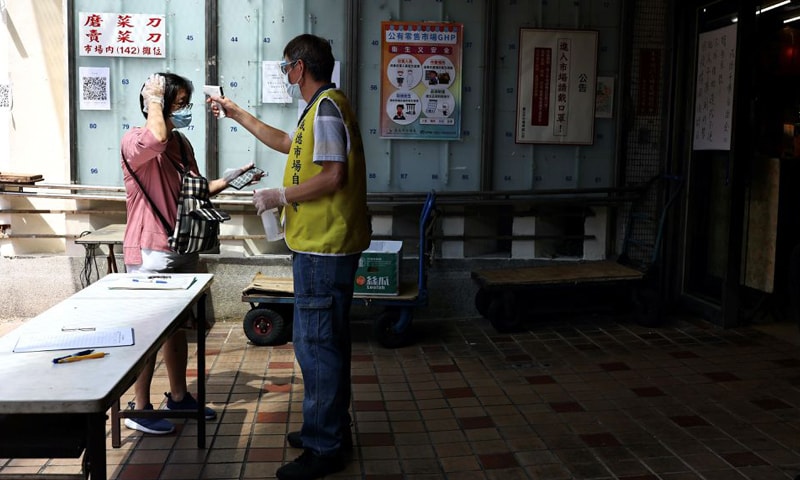 A woman gets her temperature taken while wearing a protective mask before going inside a market following the recent rise in Covid-19 cases in Taipei, Taiwan. &mdash; Reuters/File