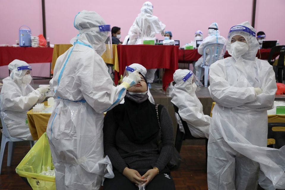 A medical worker collects a swab sample from a woman to be tested for Covid-19 in Cyberjaya on June 2. &mdash; Reuters