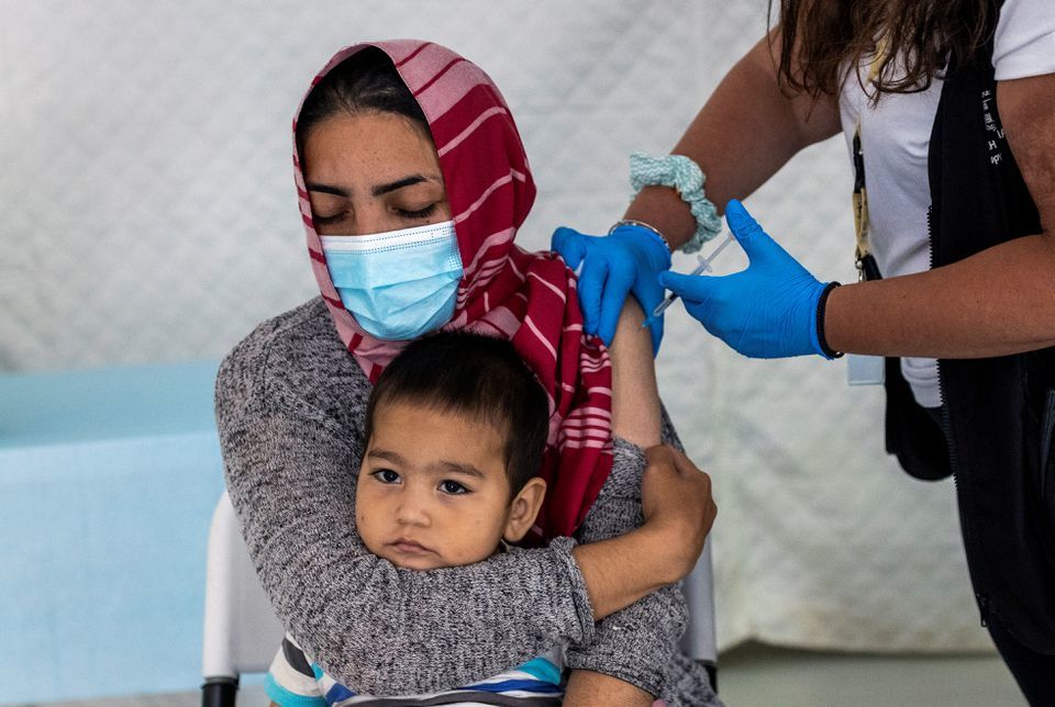A migrant holds her baby as she receives a shot of the Johnson and Johnson vaccine against the coronavirus in the Mavrovouni camp for refugees and migrants on the island of Lesbos, Greece, June 3. &mdash; Reuters