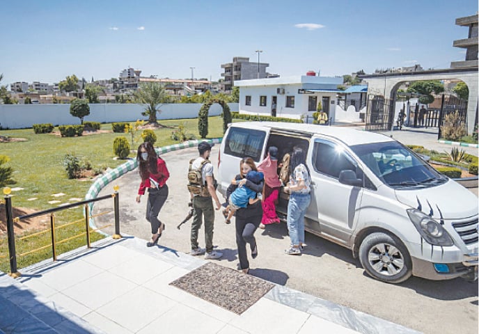 Members of Kurdish security forces accompany relatives of fighters of the militant Islamic State group, before handing them over to a delegation of Dutch diplomats in Syria&rsquo;s northeastern city of Qamishli, on Saturday. Syria&rsquo;s Kurds handed four relatives of IS fighters, including three children, to Dutch diplomats for repatriation, a thorny issue for authorities in the Netherlands.&mdash;AFP
