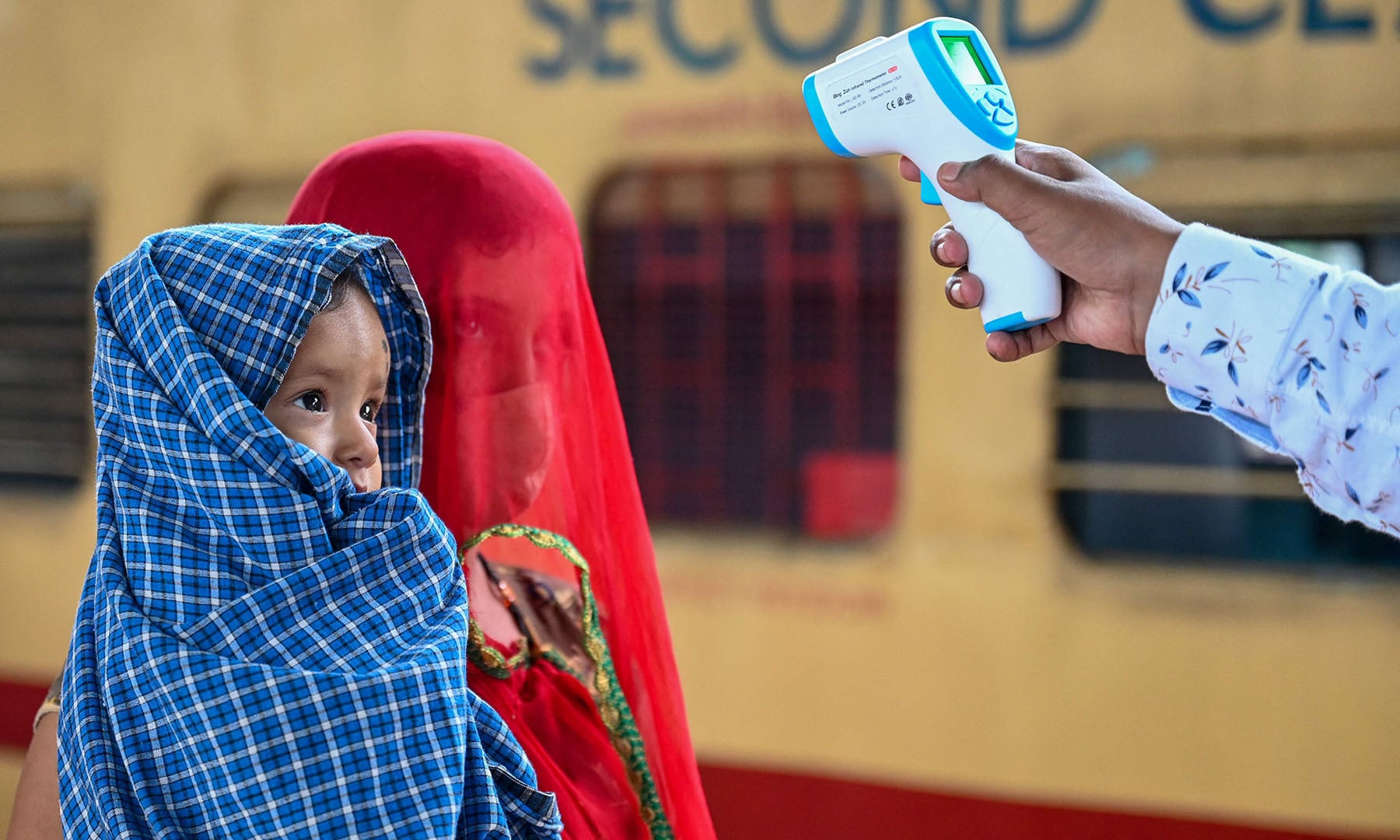 A health worker checks the body temperature of a passenger during a Covid-19 screening as she arrives with her child at a railway platform on a long distance train, in Mumbai on June 8, 2021. — AFP A health worker checks the body temperature of a passenger during a Covid-19 screening as she arrives with her child at a railway platform on a long distance train, in Mumbai on June 8, 2021. — AFP
