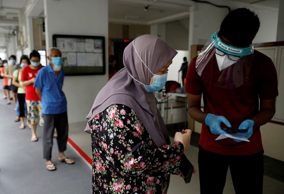 Residents of a public housing estate queue up for mandatory coronavirus swab tests in Singapore, May 21. &mdash; Reuters