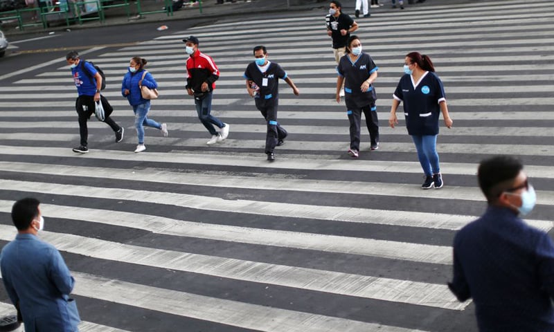 People wearing face masks cross a street as Mexico City's authorities announce a full reopening of the city come Monday. — Reuters