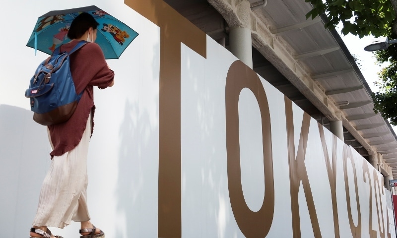 A woman walks outside the security fence of Olympic Stadium built for Tokyo Olympic Games on June 11. &mdash; Reuters