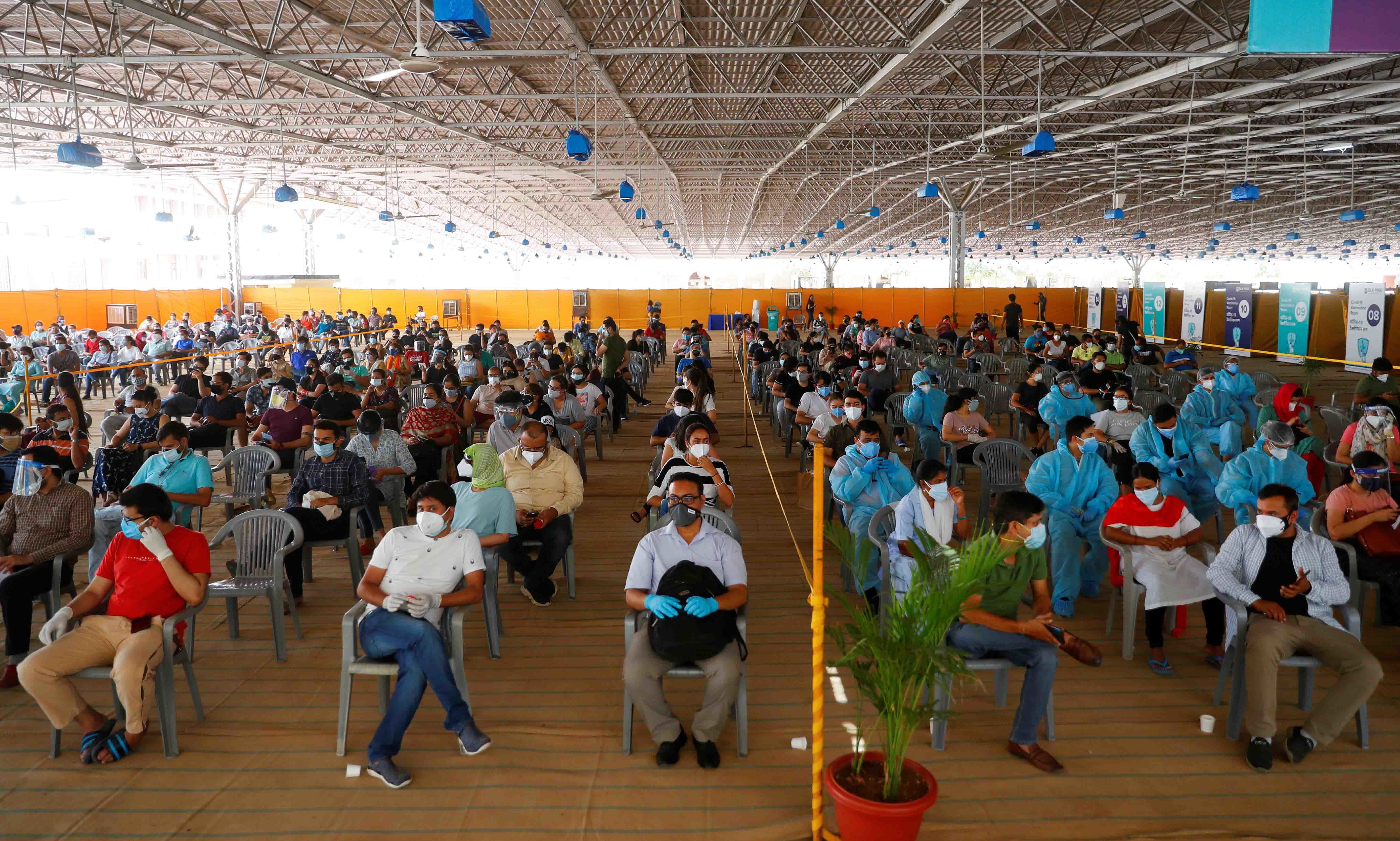 People wearing protective face masks wait to receive a dose of Covishield, a coronavirus vaccine manufactured by Serum Institute of India, at a vaccination centre in New Delhi. &mdash; Reuters