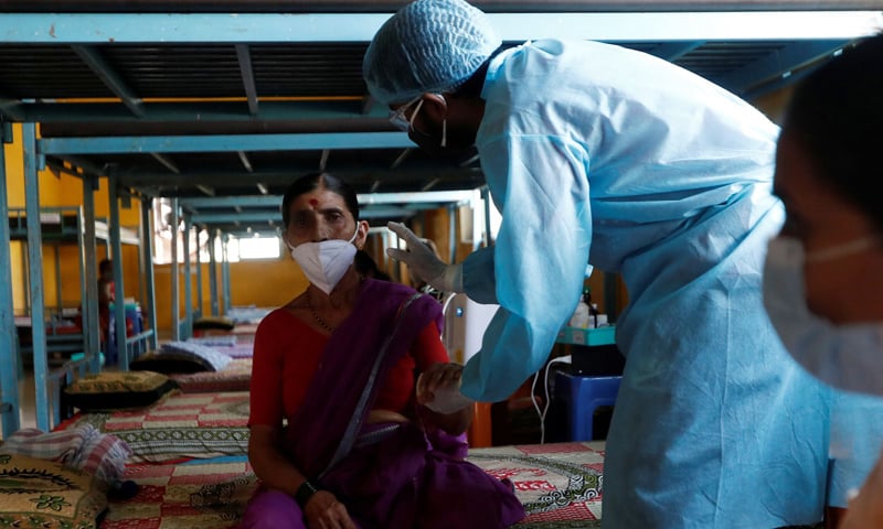 A doctor inspects a patient suffering from Covid-19 inside a classroom turned Covid-19 care facility on the outskirts of Mumbai, India. — Reuters/File