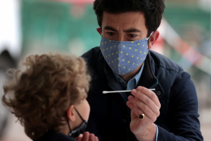 A man takes a swab sample for the coronavirus from his son at a surge testing site in London, Britain, May 14. — Reuters