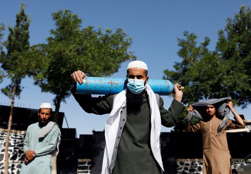 A man waits outside a factory to get his oxygen cylinder refilled as he holds it on his shoulder, in Kabul, Afghanistan. — Reuters