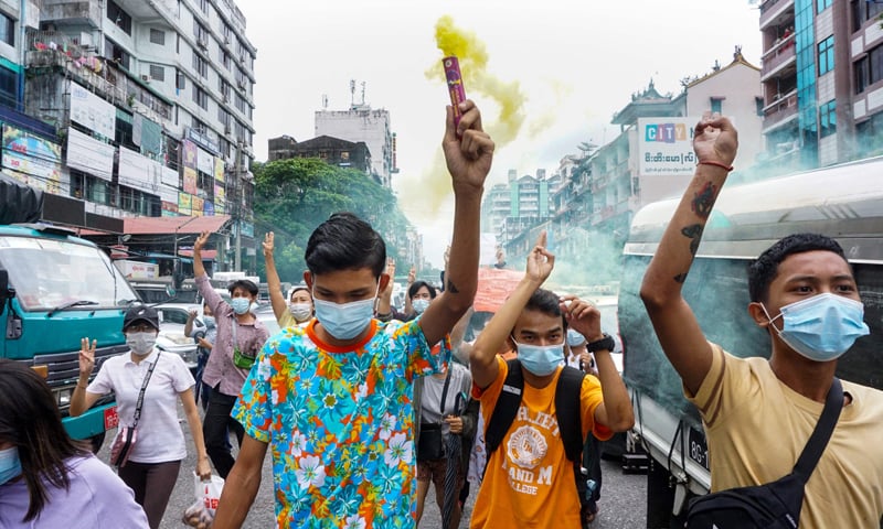 A protester holds a flare as others make the three-finger salute during a demonstration against the military coup in Yangon. &mdash; AFP