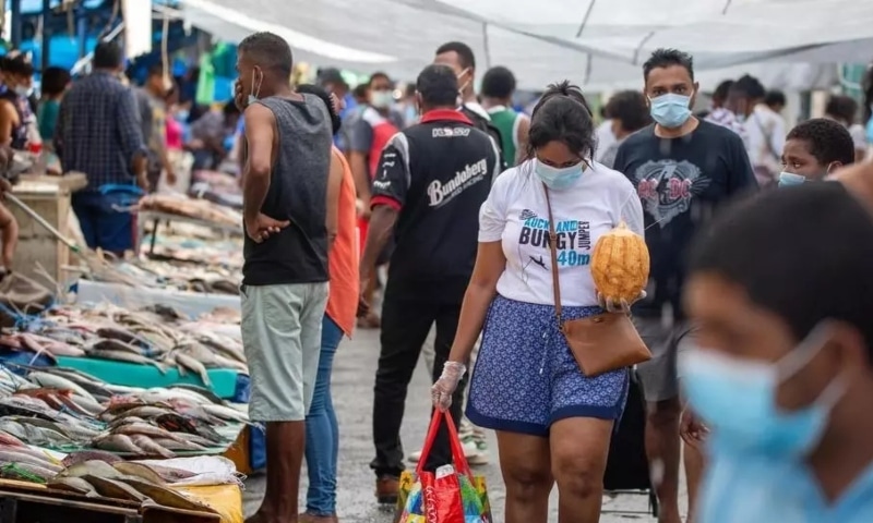 Residents in Suva, Fiji, wear masks as they walk through the fish market. — AFP