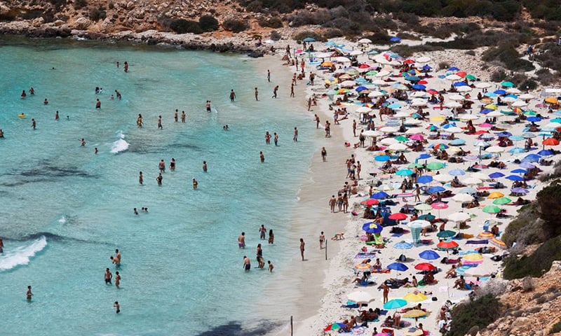 People sunbathe on the beach on the Sicilian island of Lampedusa, as a flow of migrants arriving on the Mediterranean island, in Lampedusa, Italy, June 22, 2021. &mdash; Reuters.