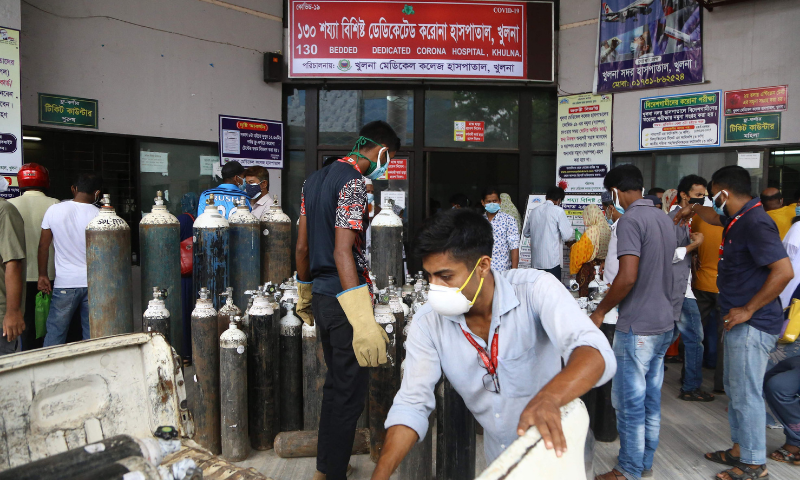 Men unload medical oxygen cylinders at the entrance of a government hospital dedicated to treat Covid-19 coronavirus patients in Khulna on Monday. — AFP