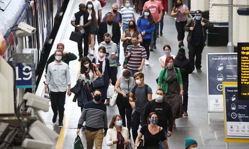 People, some wearing protective face masks, walk through Waterloo Station amid the Covid-19 pandemic in London, Britain. — Reuters