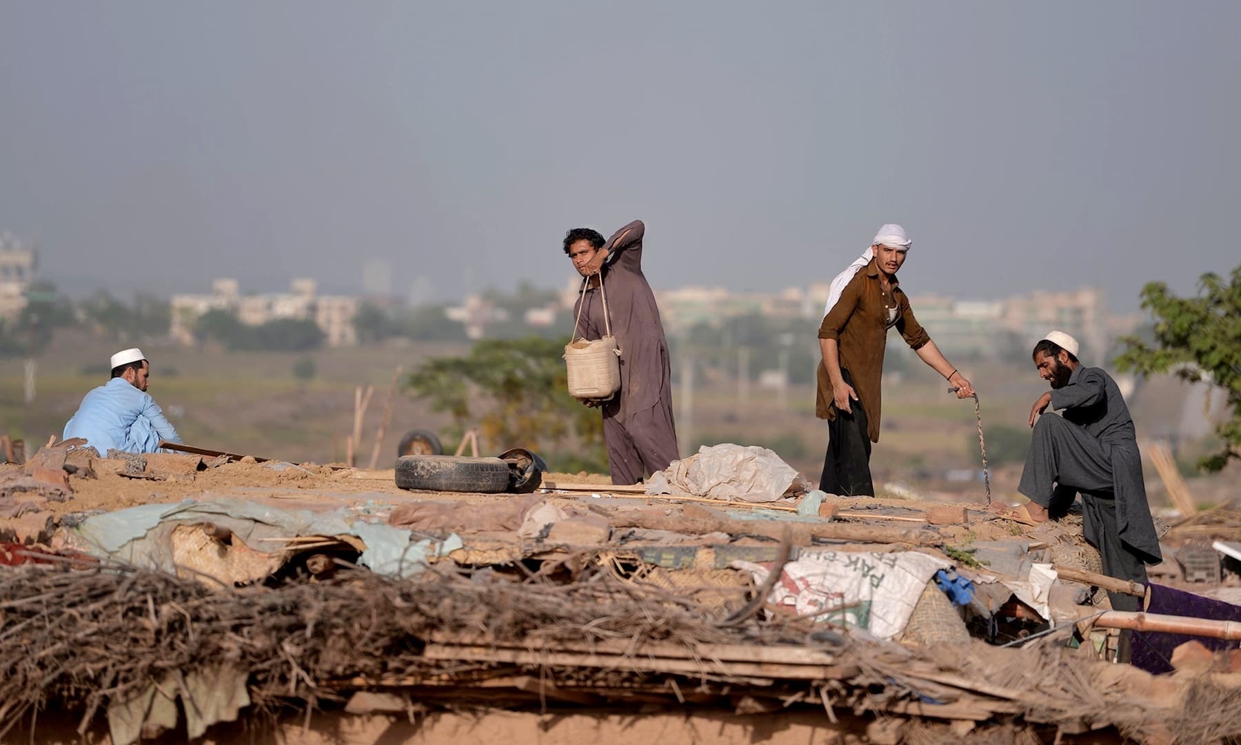 In this file photo, Afghan refugees make a roof for a mud house at a refugee camp. — AFP/File