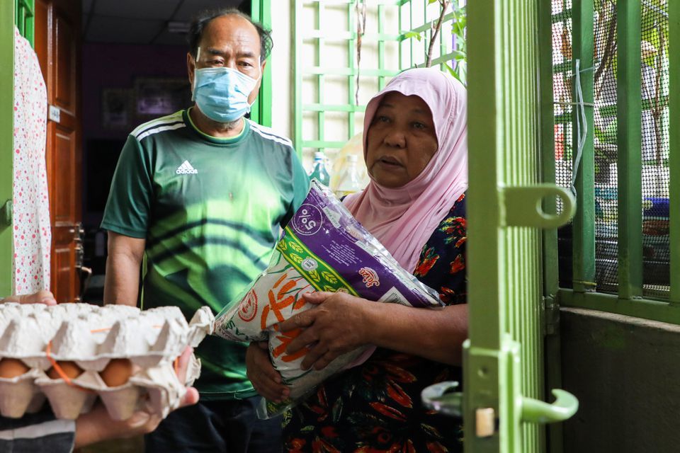 Halijah Naemat, 74, receives food supplies after she hung a white flag outside her home asking for help during an enhanced lockdown in Petaling Jaya, Malaysia, July 6. — Reuters