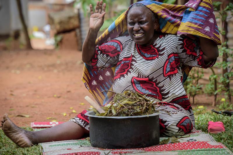 A woman reacts after covering herself to inhale steam from an infusion made from local herbs believed by her to prevent and treat the symptoms of Covid-19, in Kampala, Uganda, July 6. &mdash; AP