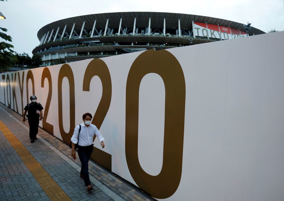 Pedestrians wearing protective masks walk in front of the National Stadium, the main stadium of Tokyo 2020 Olympics and Paralympics in Tokyo, Japan, July 7. — Reuters