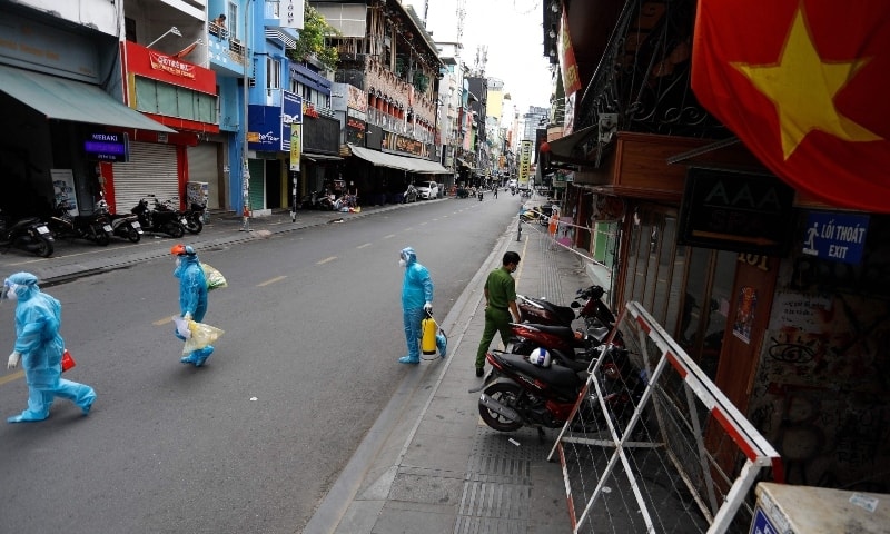 Medical workers collecting test samples from residents walk past in Ho Chi Minh City on July 9. — AFP