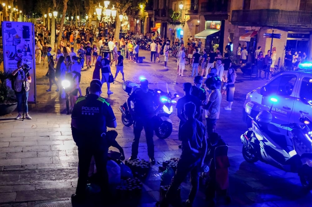 Police officers confiscate beer cans that street vendors sell to tourists and locals gathering on a street in the Born neighborhood, as indoor nightlife venues were shut again by Catalonia's regional government in a bid to stop the increase of Covid-19 cases in Barcelona on July 10. — Reuters