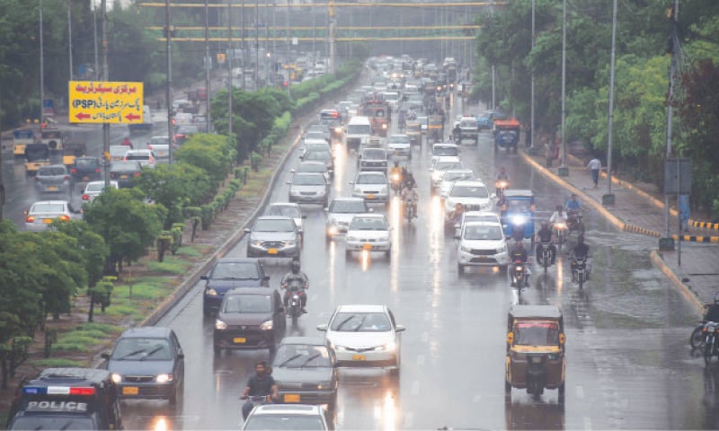 Monday morning’s rainfall is seen in this Online photo and (right) vehicles navigate a flooded road at Qayyumabad (Shakil Adil/White Star).