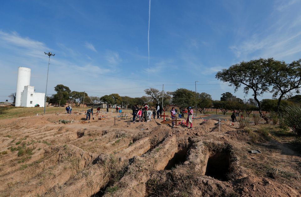 Relatives of people who died from Covid-19 are pictured next to new graves at the San Vicente cemetery, in Cordoba, Argentina, July 11. — Reuters