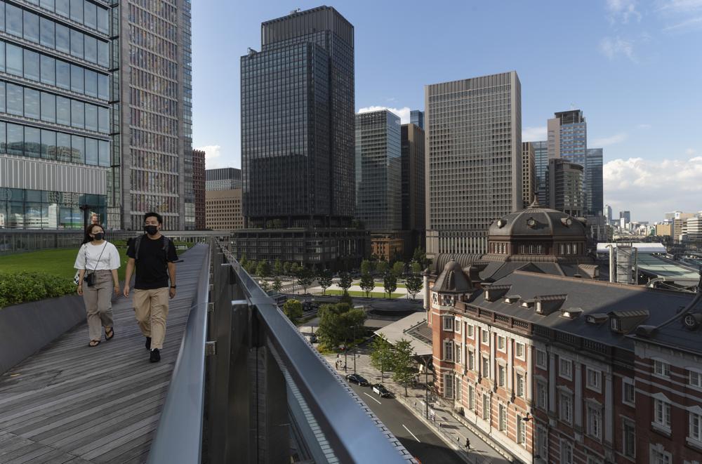 A man and a woman wearing face masks visit the rooftop park of a commercial building across from Tokyo Station, right, in Tokyo, Japan, July 15. &mdash; AP