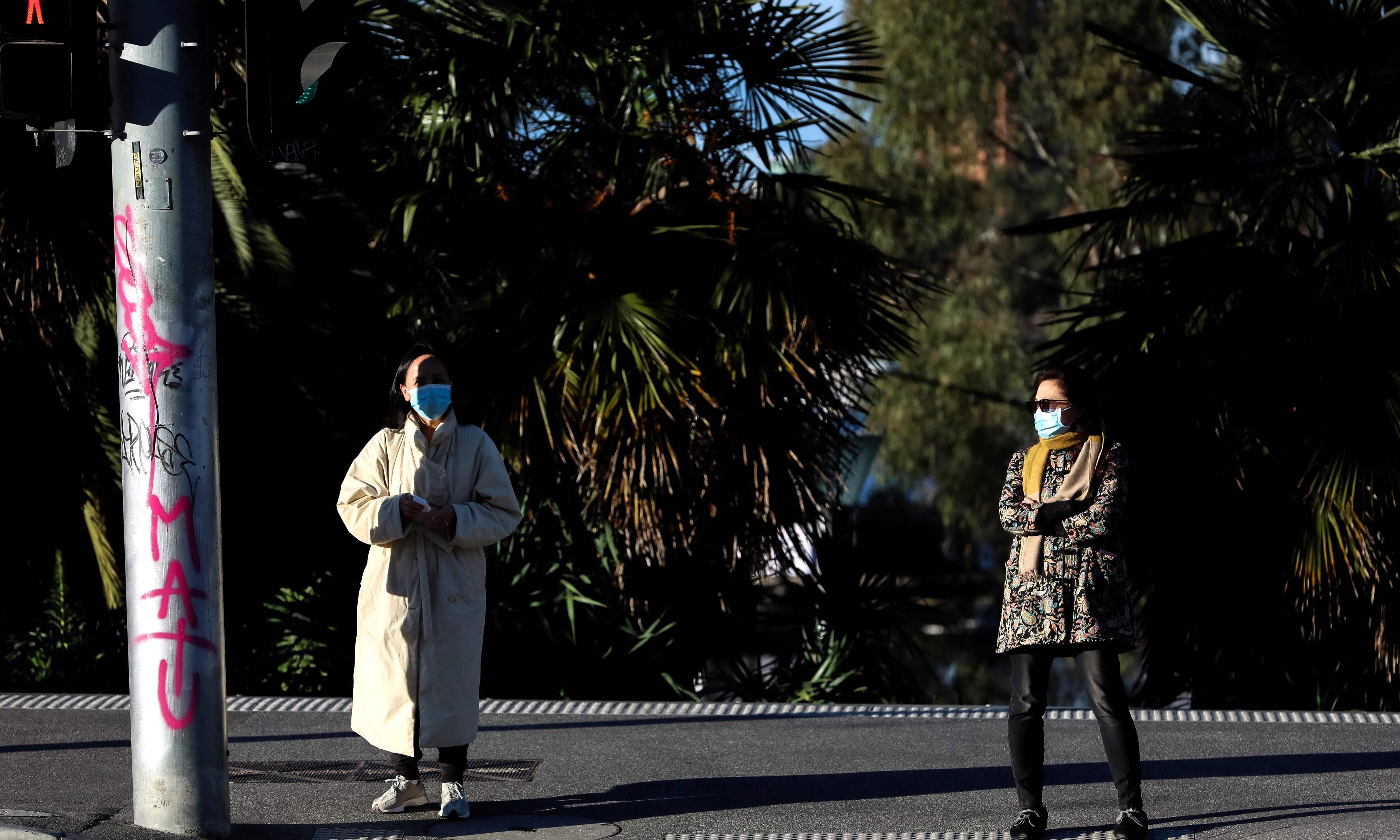 This picture shows face mask-clad pedestrians maintaining distance at a traffic light in the Southbank area of Melbourne following a fresh lockdown amid a resurgence in coronavirus cases. — AFP