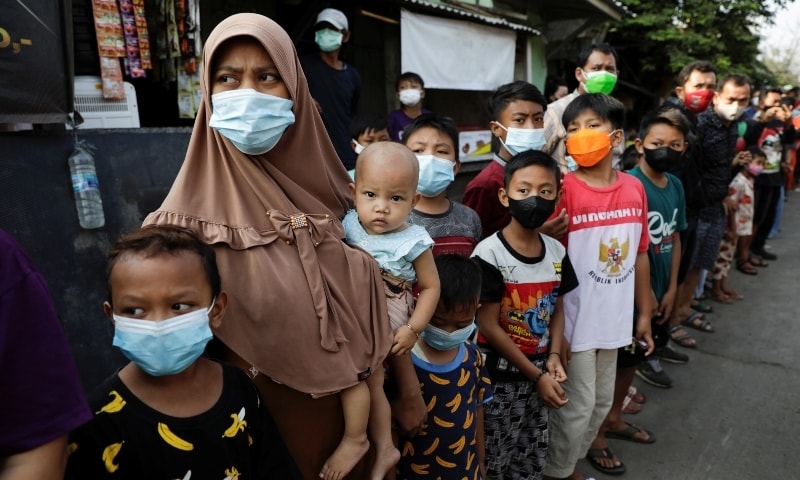 Locals wearing protective masks, to prevent the spread of coronavirus, stand in line to receive assistance from Indonesian president in Jakarta on July 16. — Reuters
