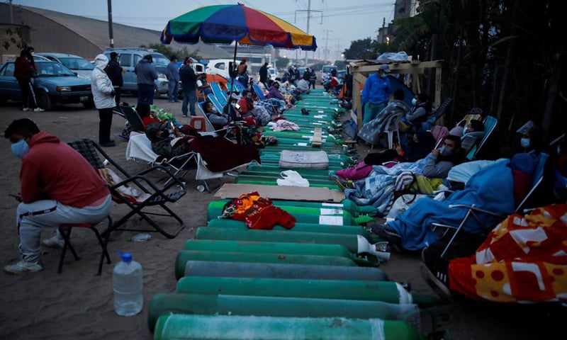People wait next to empty oxygen tanks to fill them up for patients suffering from Covid-19 outside a private oxygen supplier facility in Lima, Peru. — Reuters/File