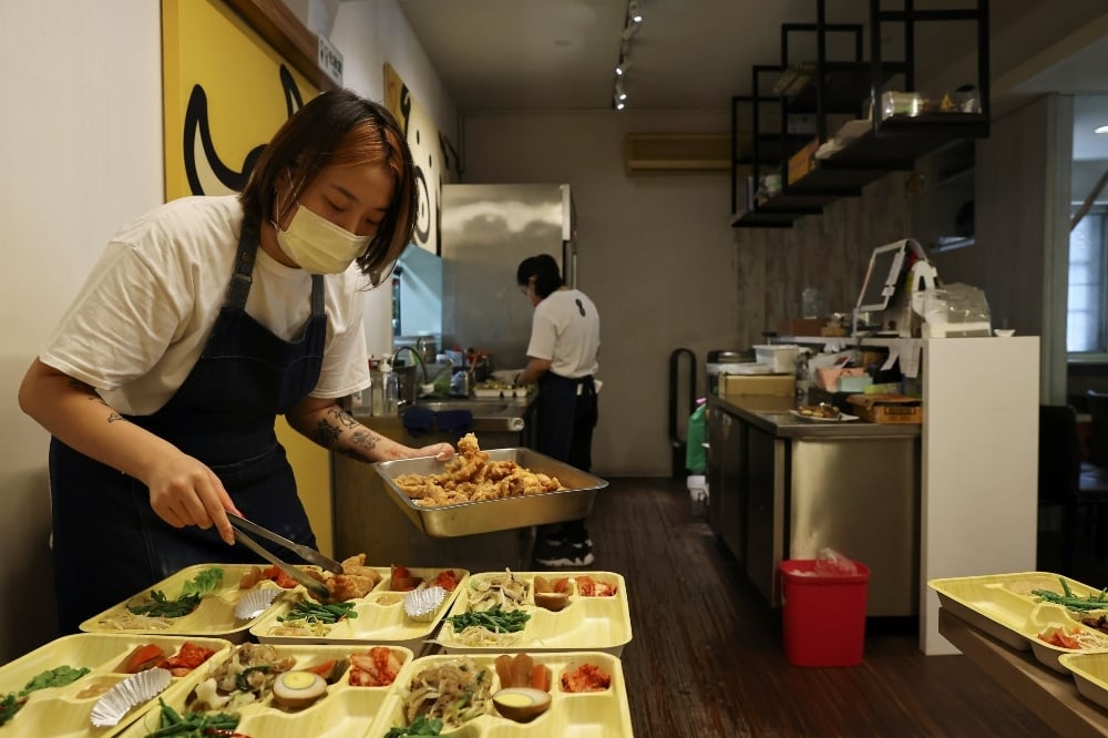 A staff member wearing a protective mask prepares take-out lunchboxes as indoor dining is restricted due to the coronavirus, at a Korean restaurant in Taipei, on July 9. &mdash; Reuters