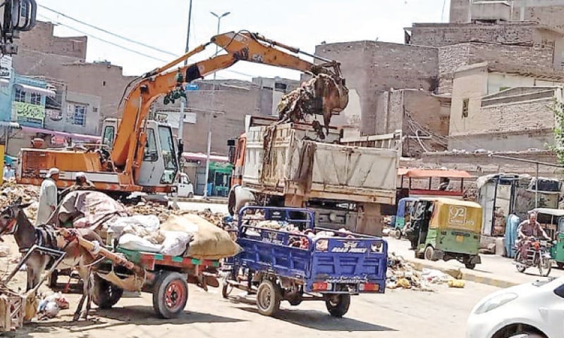 Workers of the Water and Sanitation Services Peshawar load the animal waste onto a dumper in Asia Gate area of Peshawar. &mdash; Dawn
