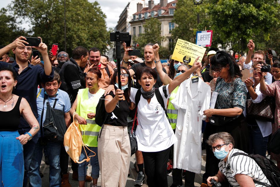 Protesters hold placards and banners during a demonstration called by the "yellow vest" (gilets jaunes) movement against France's restrictions to fight the coronavirus outbreak in Paris, France, July 24. &mdash; Reuters