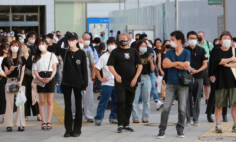 People wearing face masks to protect against the spread of the coronavirus stand at an intersection in Tokyo on July 27. — AP