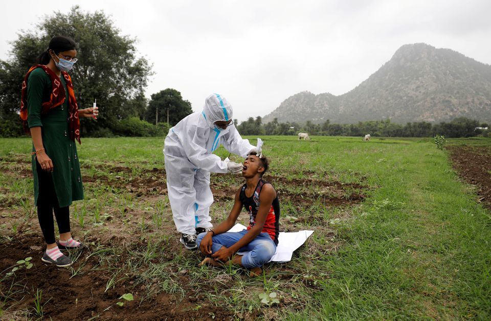 A healthcare worker collects a swab for a rapid antigen test from a farmer in his field, during a door-to-door vaccination drive in Banaskantha district in the western state of Gujarat, India, July 23. — Reuters