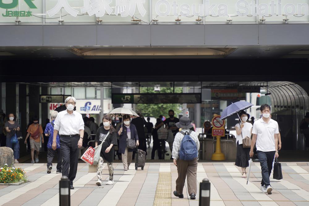 People wearing face masks to help curb the spread of the coronavirus walk around Otsuka Station in Tokyo, Japan, July 30. — AP