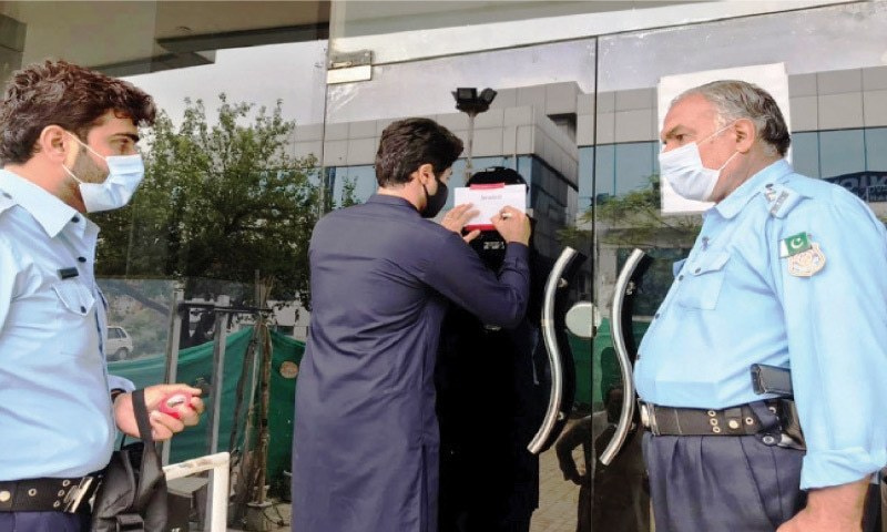 An official of the capital administration seals the office of Therapyworks in Islamabad on the orders of Deputy Commissioner Hamza Shafqaat on July 25. — White Star/File