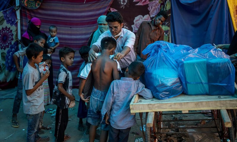 A Rohingya activist distributes new clothes among refugees at a refugee camp alongside the banks of the Yamuna River in the southeastern borders of New Delhi, India. &mdash; AP/File