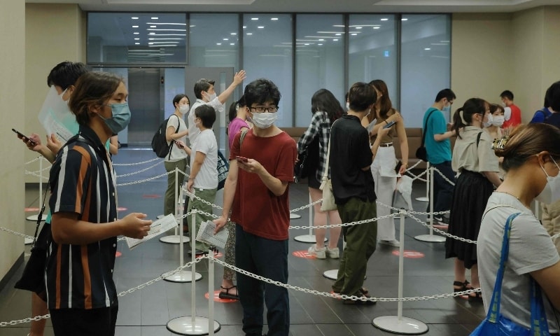 People queue up before receiving a dose of the coronavirus vaccine at Aoyama University in Tokyo on August 2. — AFP