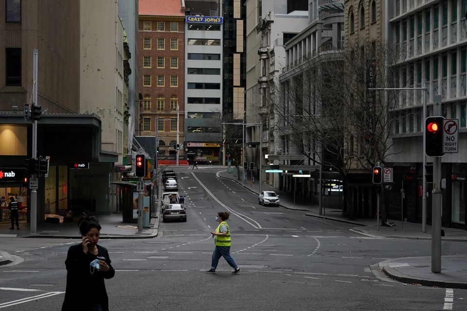 People with protective face masks walk through the quiet city centre during a lockdown to curb the spread of a coronavirus outbreak in Sydney, Australia, July 28. &mdash; Reuters
