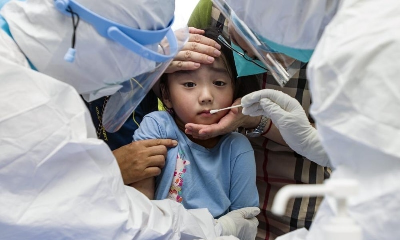 A child reacts to a throat swab during mass testing for Covid-19 in Wuhan in central China's Hubei province on August 3. — AP