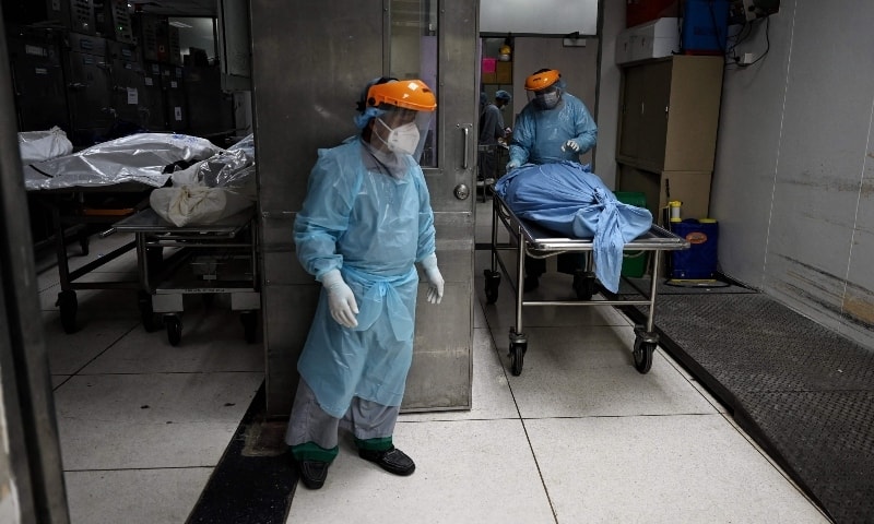 Hospital workers move the bodies of deceased persons to make space for Covid-19 victims in the overcrowded morgue in Thammasat Hospital in Pathum Thani province on August 4. — AFP