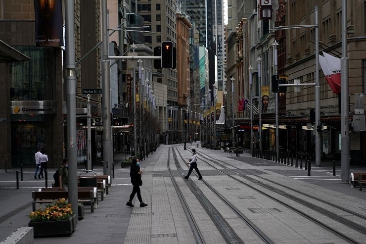People in protective face masks walk through the quiet city centre during a lockdown to curb the spread of a Covid-19 outbreak in Sydney, Australia, on July 28, 2021. — Reuters