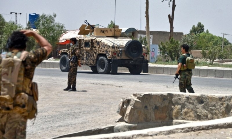 Afghan security personnel stand guard along the road amid fighting between Afghan security forces and Taliban fighters in Kandahar on July 9. — AFP