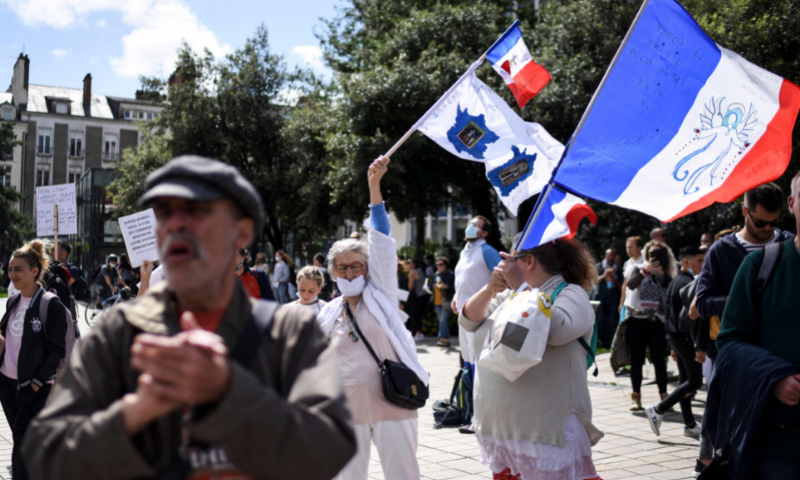 Demonstrators hold a French flag during a national day of protest against the compulsory Covid-19 vaccination for certain workers and the mandatory use of the health pass called for by the French government in Nantes, western France on Saturday. — AFP