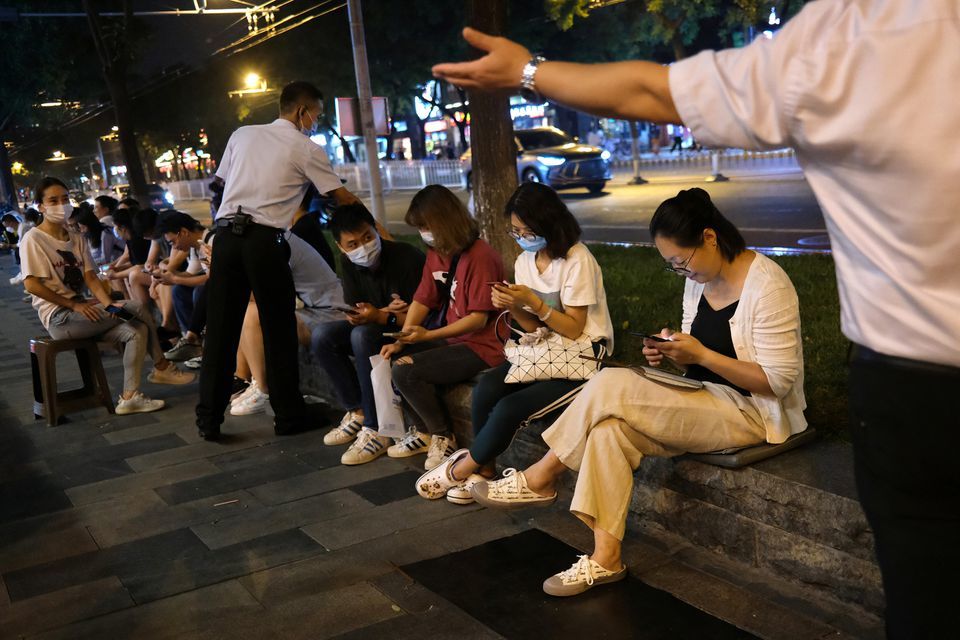 People wait in front of a restaurant, following an outbreak of the coronavirus in Beijing, China on August 13. — Reuters