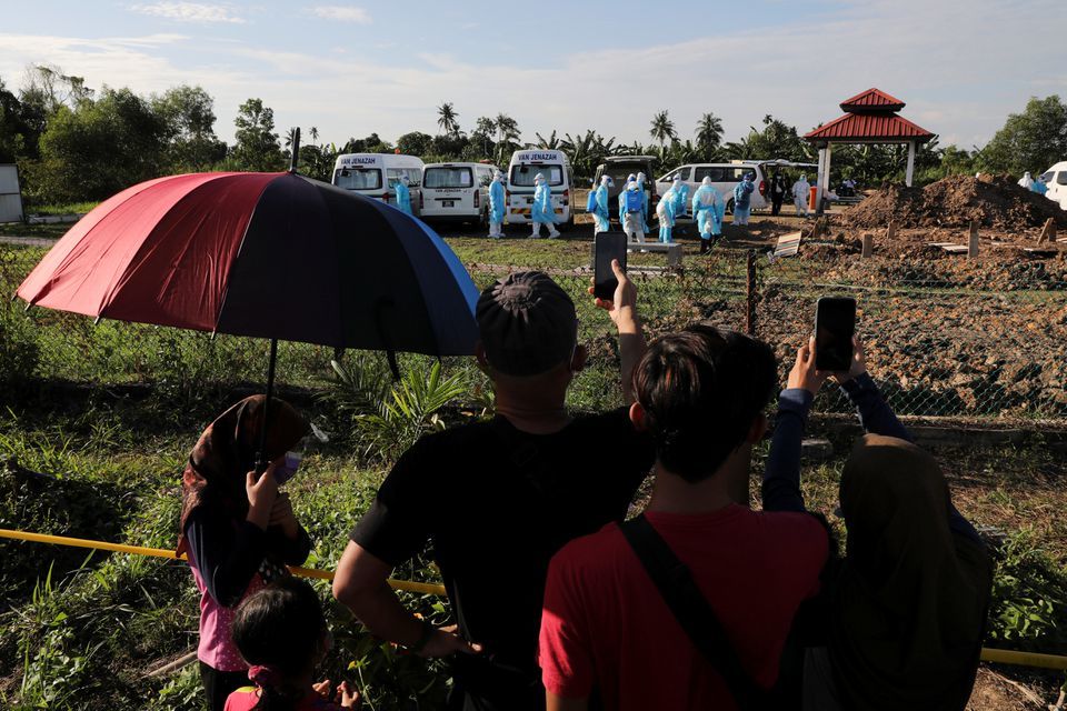 Family members attend the burial of their relative who died from the coronavirus outside a cemetery in Klang, Malaysia on August 5. — Reuters